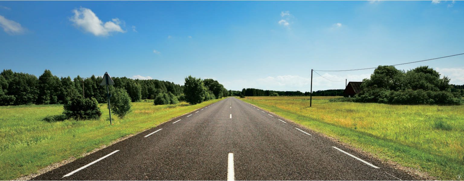 Paved rural road through green fields